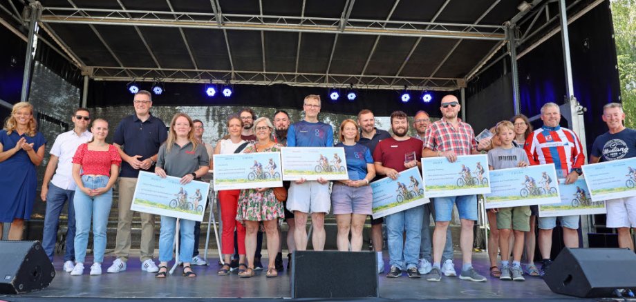 Menschen stehen mit Urkunden auf eienr Bühne.