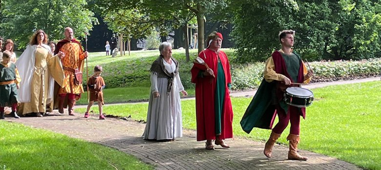 Italienische Besucher in bunter traditioneller Kleidung. Der fordere Mann trommelt.