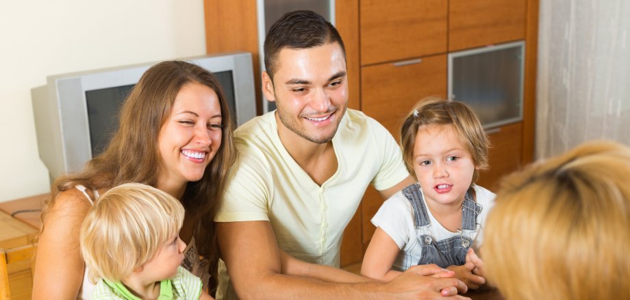 Junge Eltern mit zwei Kindern werden von einem Sozialarbeiter beraten.