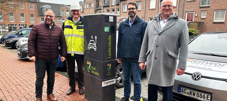 Menschen stehen lächelns vor der E-Ladesäule