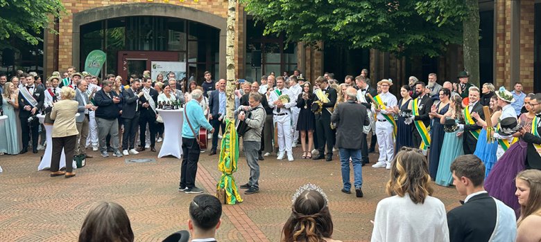 Viele Menschen stehen auf dem Morlaixplatz um den Maibaum herum und singen.