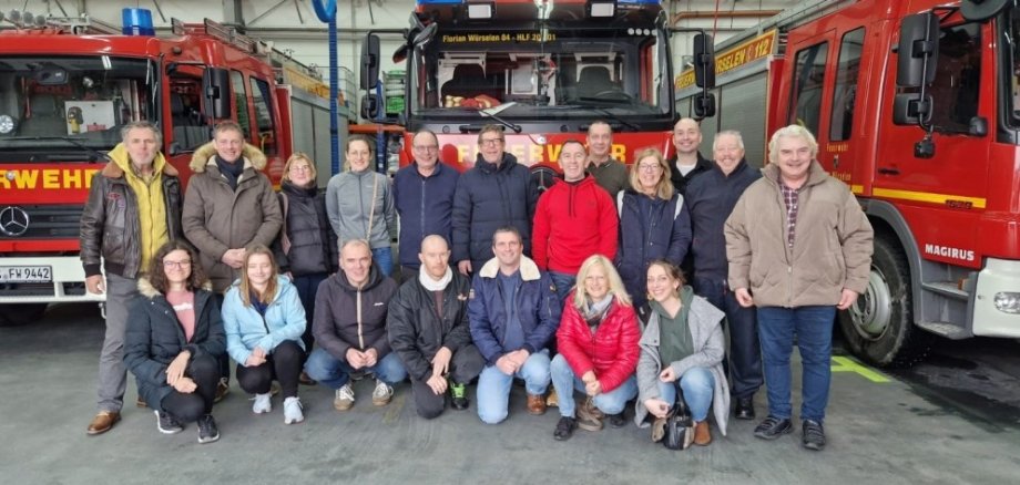 Menschen stehen vor einem Einsatzwagen der Feuerwehr.