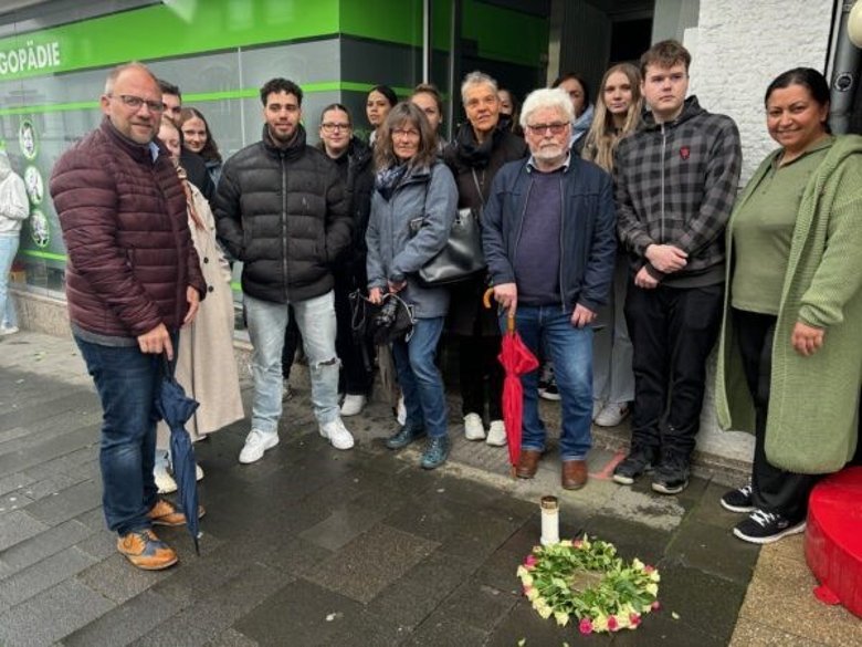 Eine Gruppe Menschen stehen neben einem Stolperstein.