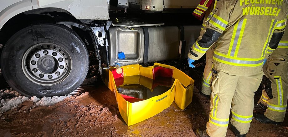 Beschädigter LKW nach Unfall mit einer Auffangschale für Benzin und 3 Feuerwehrleute