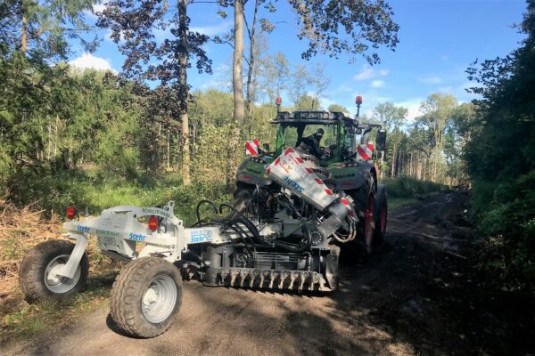 Ein Traktor mit Arbeitsgerät auf einem Waldweg